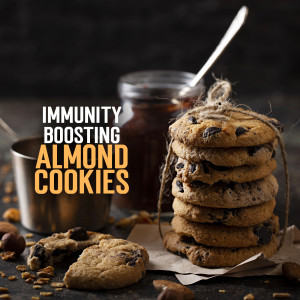 A stack of chocolate chip almond cookies with a jar of jam and a cup of coffee.