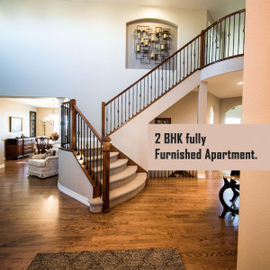 Interior view of a modern 2 BHK apartment with a curved staircase and hardwood floors.