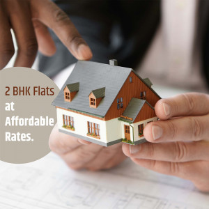 A miniature house model held in hands with text '2 BHK Flats at Affordable Rates'