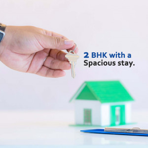 Hand holding a key with a miniature house representing a 2 BHK property