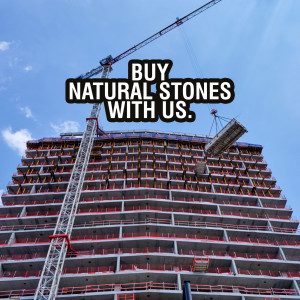 Construction site with a crane and a banner advertising natural stones.