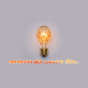 Vintage light bulb glowing against a gray background with Malayalam text.