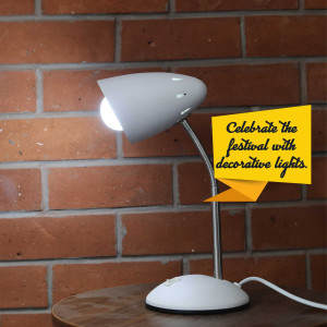 White desk lamp illuminating a brick wall with a festive message