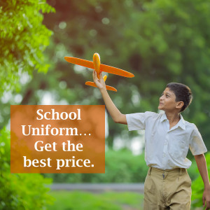 A young boy in a school uniform looking up at an orange paper airplane.