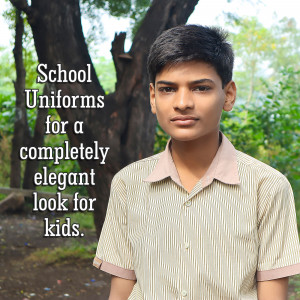 A young male student wearing a school uniform stands in front of a tree.