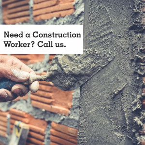 Close-up of a construction worker applying mortar to a brick wall.