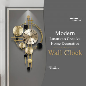 A modern, luxurious gold and black wall clock against a gray wall.