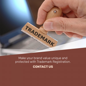 Hand stamping the word 'TRADEMARK' onto paper with a wooden stamp, representing trademark registration.