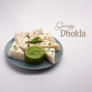 A plate of spongy dhokla with green chutney