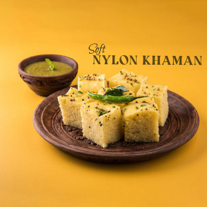 Close-up of a plate of soft nylon khaman, a traditional Gujarati snack, served with green chutney and garnished with green chilies.