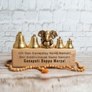 Ganesh idol with bells and prayer beads on a wooden platform