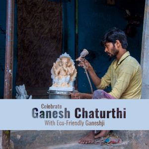 An artisan painting an eco-friendly Ganesha idol with a spray gun.