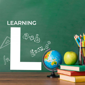 A still life of school supplies on a wooden desk with a green chalkboard background.