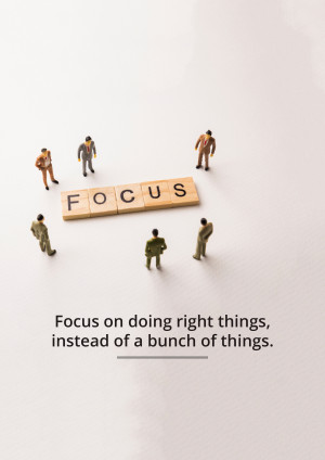 Miniature figures surrounding the word 'FOCUS' made of letter blocks, with motivational text below.