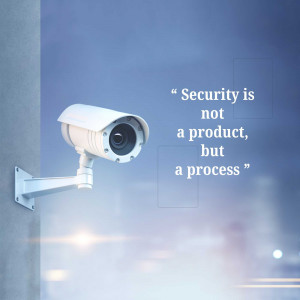 A security camera mounted on a white wall with a quote about security.