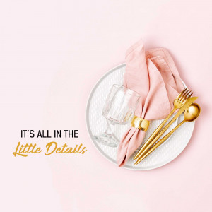Overhead view of a beautifully set table with gold cutlery, a pink napkin, and a glass.