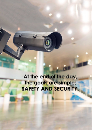 Close-up of a security camera monitoring a building lobby with text overlay 'At the end of the day, safety and security.'