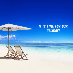 Two lounge chairs under a white umbrella on a tropical beach with turquoise water.