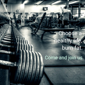 Rows of dumbbells in a gym with people working out in the background and motivational text.