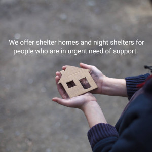 Hands holding a wooden house representing shelter for those in need.