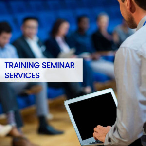 A man presenting at a business training seminar with attendees in the background.