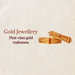 Close-up of two gold bangles with red stone detailing
