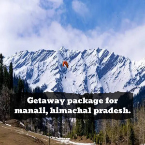 A paraglider soaring over snow-capped mountains in Manali, Himachal Pradesh.