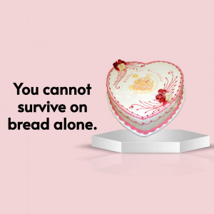 A heart-shaped cake with a quote 'You cannot survive on bread alone' displayed on a pedestal.