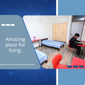 A student studying in a simple, clean room in a shared living space.