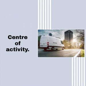 White delivery van driving on a city street with skyscrapers in the background.