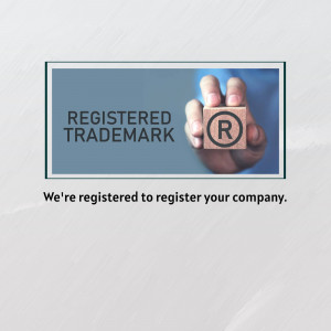 Hand holding wooden blocks spelling 'Registered Trademark' with a trademark symbol.
