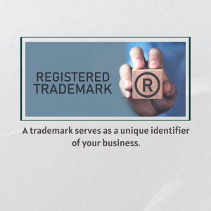 Hand holding a wooden cube with a registered trademark symbol.