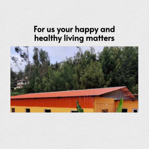 A building with a red roof and yellow walls set against a lush green hillside.