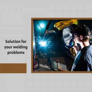 A welder using robotic welding equipment in a workshop.