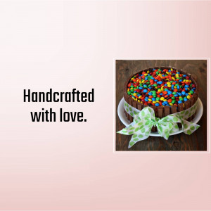 A round chocolate cake covered in colorful candies and decorated with a light green ribbon.