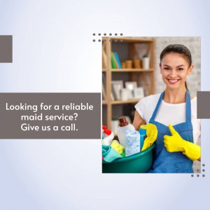 Smiling maid holding cleaning supplies and giving a thumbs up.