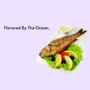 Grilled fish served with lemon, olives, and a side of sauce on a white plate.