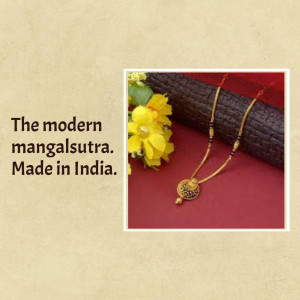 Close-up of a modern gold mangalsutra with black beads and a pendant, resting on a textured surface with yellow flowers.