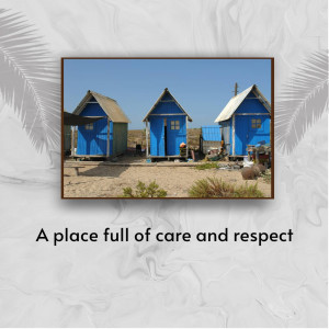 Three bright blue beach huts on a sandy shore under a clear blue sky.
