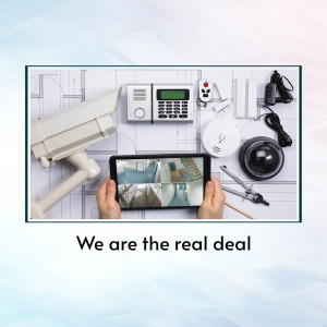 Overhead view of home security components including cameras, control panel, tablet displaying live feed, and tools.