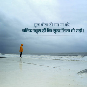 A lone figure in an orange hoodie stands on a beach under a cloudy sky with Hindi text overlayed.