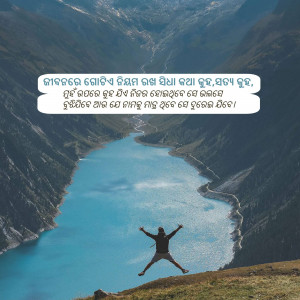 A person jumping in the air with arms outstretched in front of a stunning mountain lake and valley.