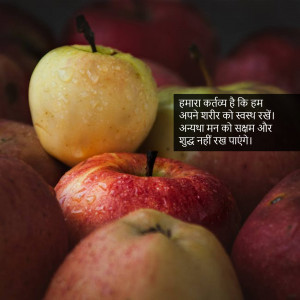 A close-up of several apples, some red and some green, with text overlay in Hindi.