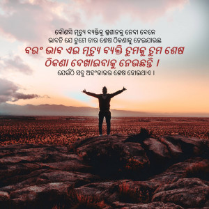 A silhouette of a man with arms outstretched standing on a rocky outcrop against a sunset backdrop.