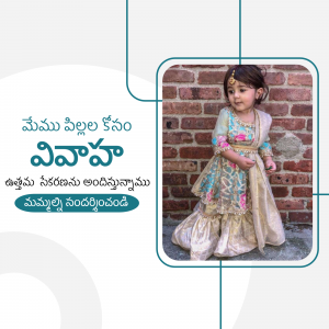 A cute little girl wearing a traditional Indian outfit posing in front of a brick wall.