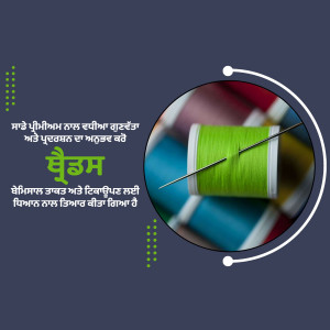 Close-up of a green spool of thread with a needle, surrounded by colorful fabrics.