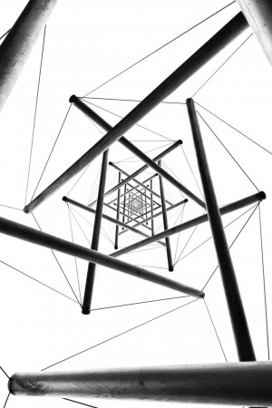 Black and white abstract image of a modern architectural structure with intersecting lines and a central focal point.