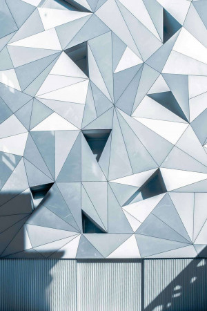 Close-up of a modern building facade with a geometric pattern of triangular panels.