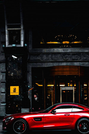 A sleek red sports car parked in front of a building at night.