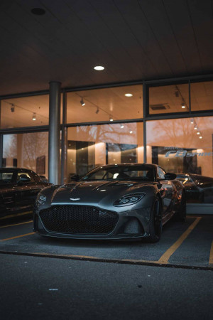 A sleek gray Aston Martin parked in a dealership showroom at night.